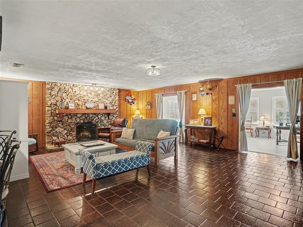 A living room features a stone fireplace, wood-paneled walls, and dark tile flooring — 1390 E OHIO AVENUE, LAKE HELEN, FL