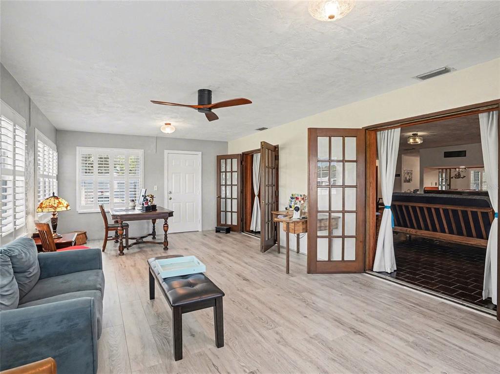 A living room with light wood-look flooring, a ceiling fan, and French doors leading outside — 1390 E OHIO AVENUE, LAKE HELEN, FL