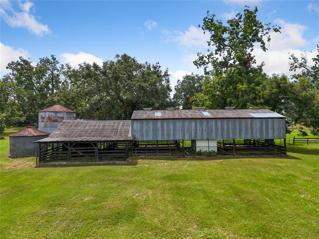 A large, weathered metal barn with an attached silo stands in a grassy field — 1845 SW HALTIWANGER ROAD, LAKE CITY, FL