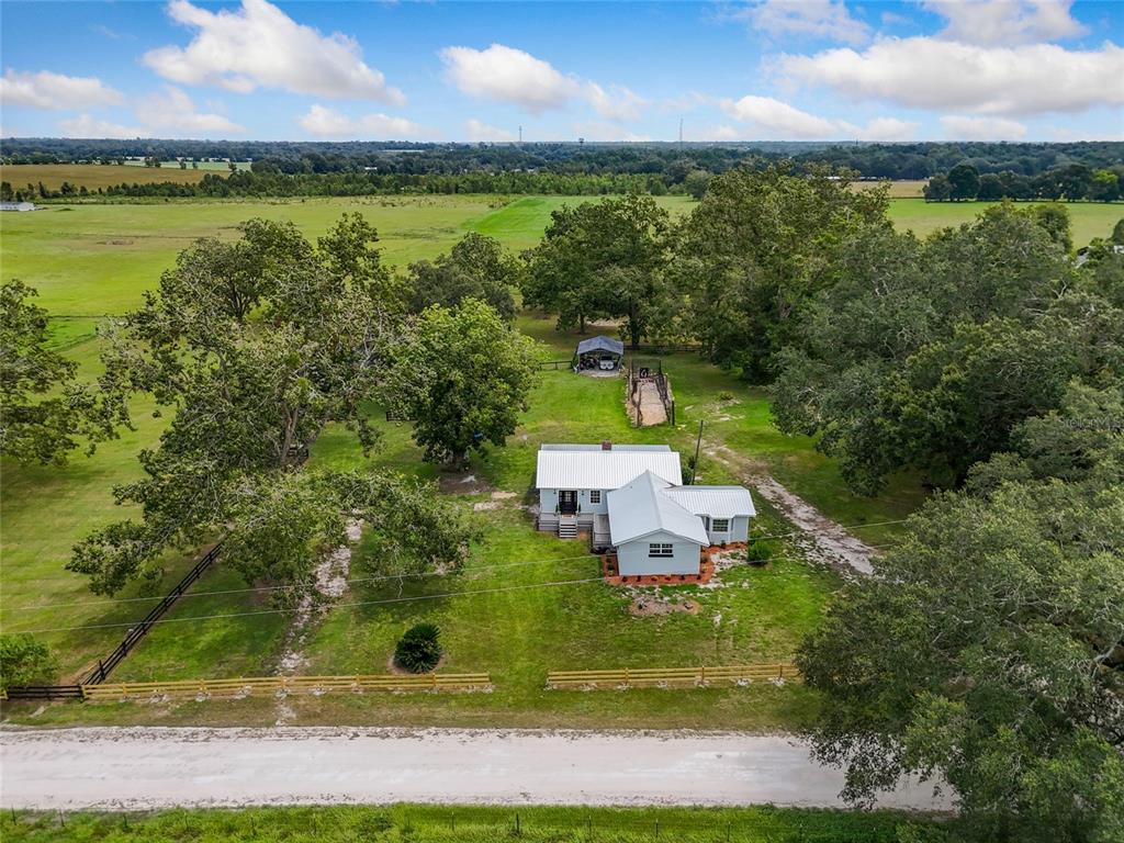 An aerial view shows a house with a metal roof surrounded by trees and pastures — 1845 SW HALTIWANGER ROAD, LAKE CITY, FL