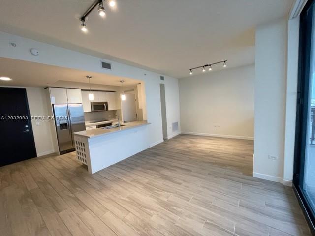 An open-concept kitchen with a white island and stainless steel appliances overlooks a living area — 999 SW 1st Ave # 3115, Miami FL 33130, MIAMI, FL