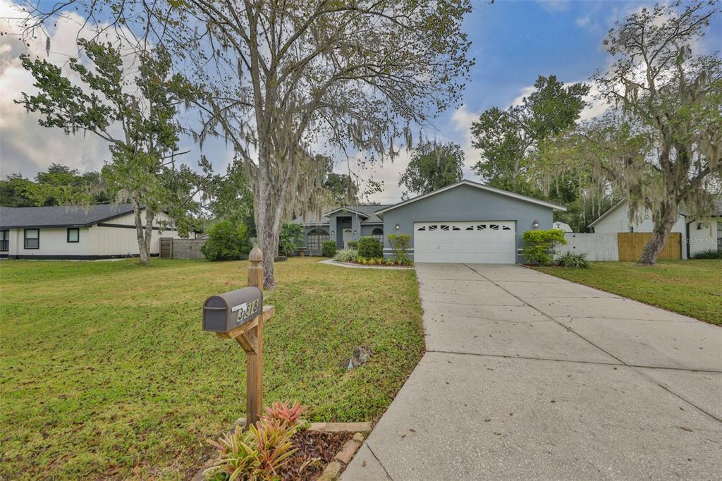 A gray single-story house with a two-car garage and Spanish moss hanging from large trees — 3818 BISCAY PLACE, LAND O LAKES, FL