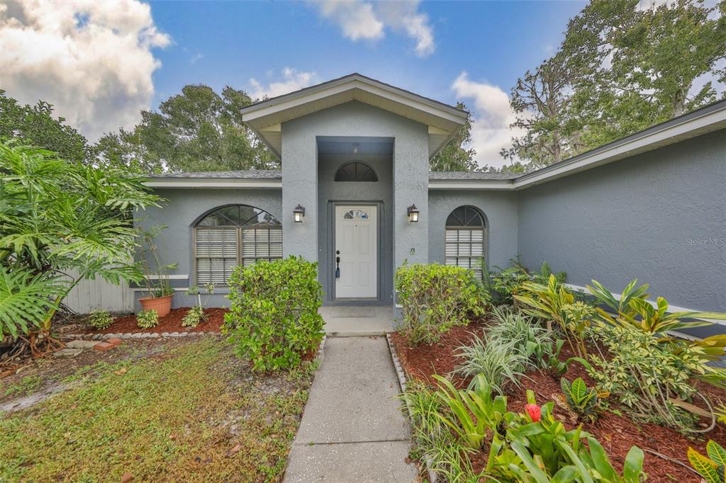A single-story house with a gray exterior, arched windows, and a front walkway — 3818 BISCAY PLACE, LAND O LAKES, FL