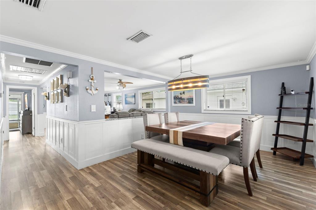 A dining room features a wooden table, upholstered chairs, a bench, and light blue walls — 5210 6TH STREET S, ST PETERSBURG, FL