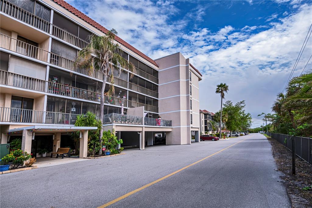 A multi-story apartment building with screened balconies and a ground-level parking area — 25188 MARION AVENUE UNIT D205, PUNTA GORDA, FL