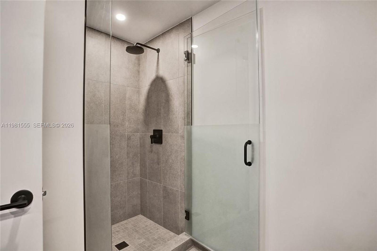 A walk-in shower features gray tiled walls, a rainfall showerhead, and a glass door — 121 NE 5 St # 801B, Miami FL 33132, MIAMI, FL