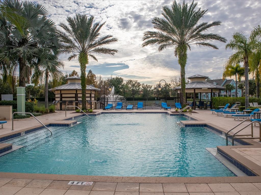 A rectangular swimming pool with a fountain and two gazebos surrounded by palm trees — 3003 LIMBO LANE UNIT #103, KISSIMMEE, FL