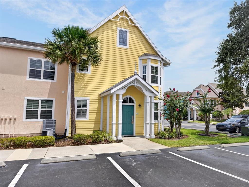 A yellow two-story building with a teal front door and a palm tree in front — 3003 LIMBO LANE UNIT #103, KISSIMMEE, FL