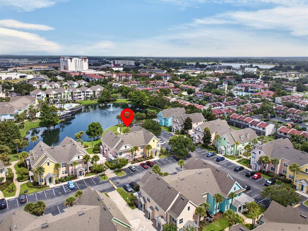 An aerial view shows multi-story residential buildings surrounding a pond with a fountain — 3003 LIMBO LANE UNIT #103, KISSIMMEE, FL