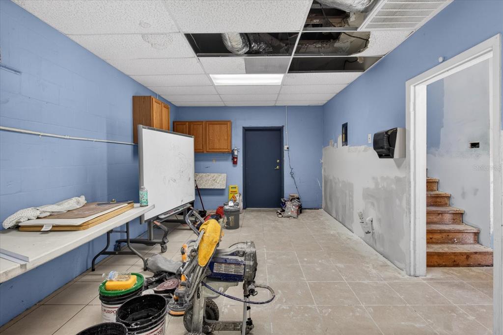 A room under renovation with blue walls, a drop ceiling, and an unfinished staircase — 2024 GRANT STREET, TAMPA, FL