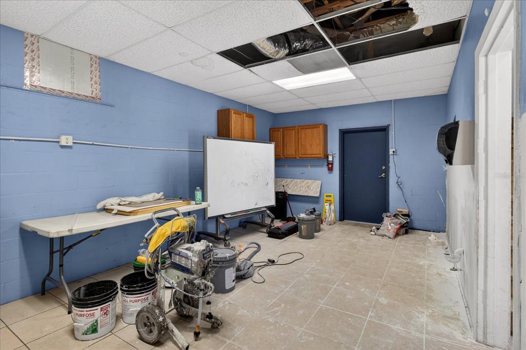 A utility room with blue block walls, a drop ceiling, and a portable paint sprayer — 2024 GRANT STREET, TAMPA, FL
