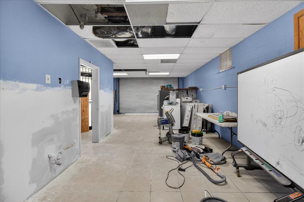 An unfinished room with blue walls, a drop ceiling, and a whiteboard on the right — 2024 GRANT STREET, TAMPA, FL