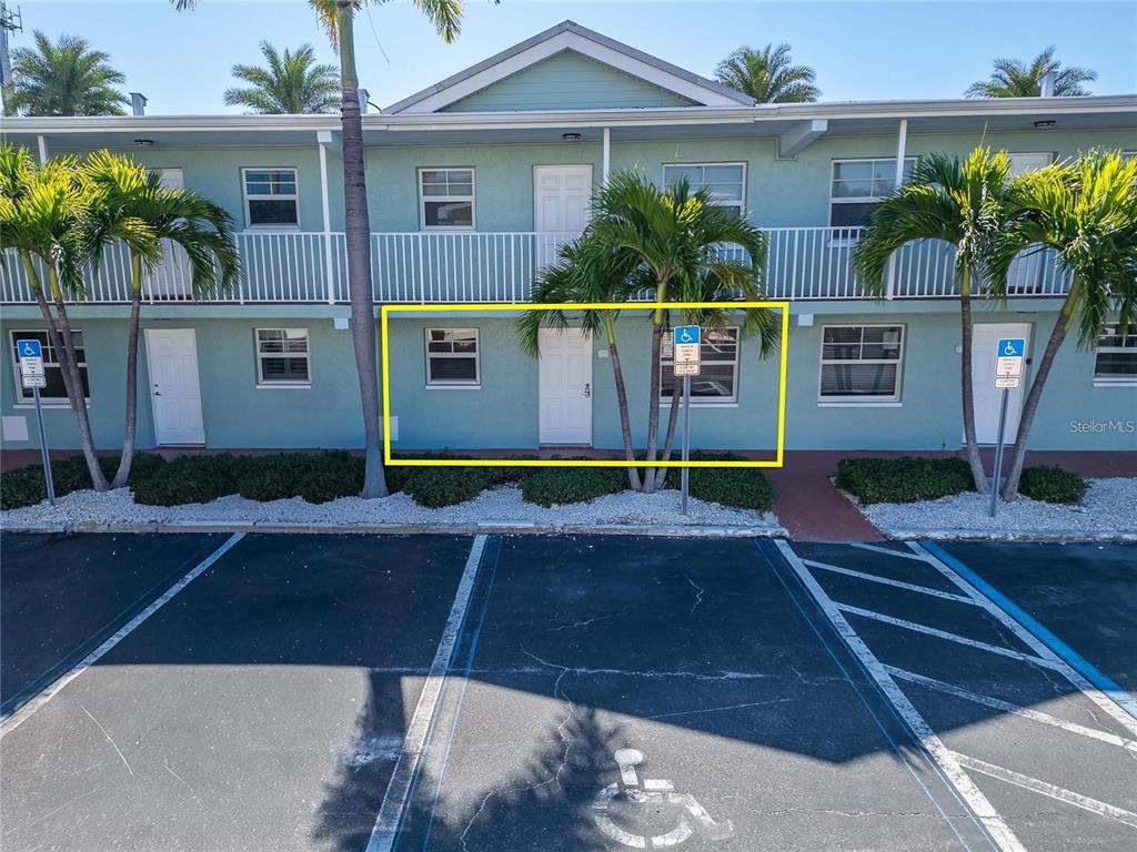 An aerial view shows a swimming pool surrounded by lounge chairs and blue shade structures — 19417 GULF BOULEVARD UNIT F110, INDIAN ROCKS BEACH, FL