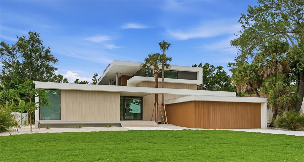 A modern two-story house with a flat roof, wood-paneled exterior, and a large front lawn — 359 N SHORE DRIVE, SARASOTA, FL