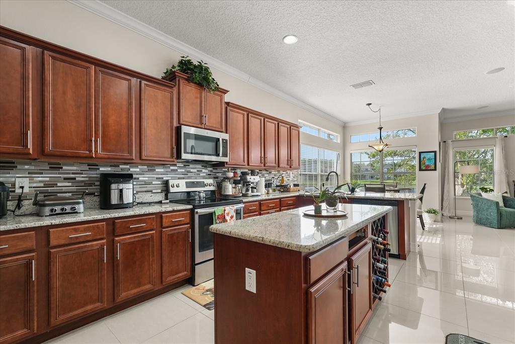 A kitchen with wood cabinets, granite countertops, a center island, and tile flooring — 16108 BRISTOL LAKE CIRCLE, ORLANDO, FL