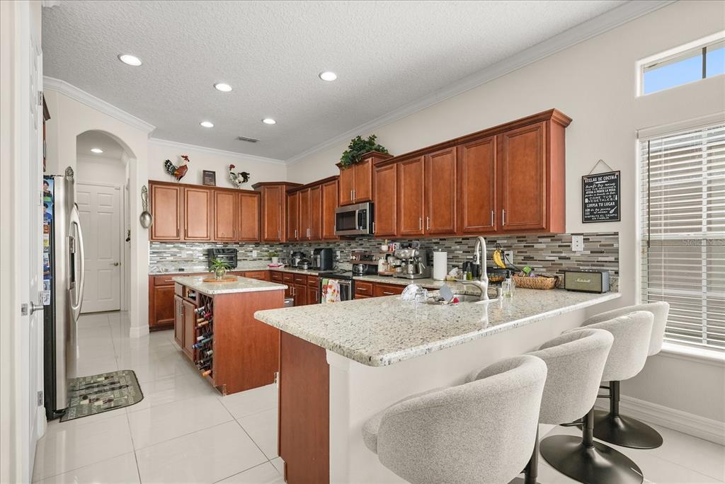 A kitchen features wood cabinets, granite countertops, a center island, and a breakfast bar — 16108 BRISTOL LAKE CIRCLE, ORLANDO, FL