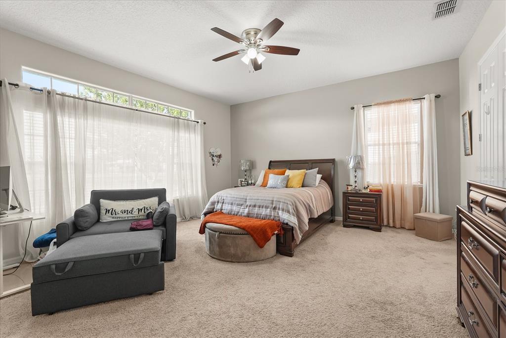 A bedroom features a bed, a gray sofa with an ottoman, and a ceiling fan — 16108 BRISTOL LAKE CIRCLE, ORLANDO, FL