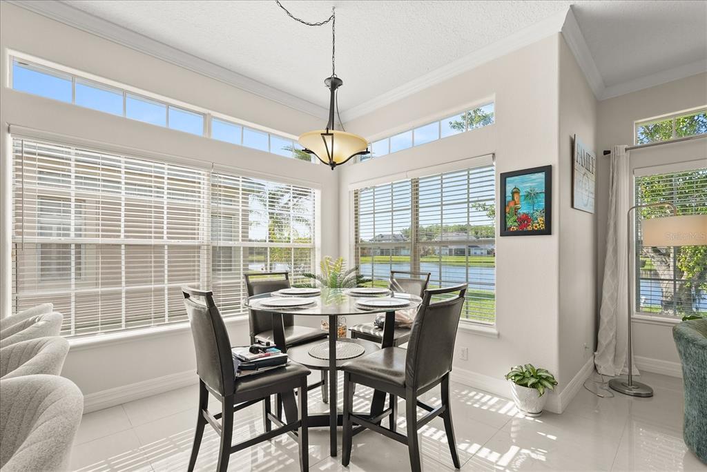 A dining area features a glass table, four chairs, large windows, and a lake view — 16108 BRISTOL LAKE CIRCLE, ORLANDO, FL