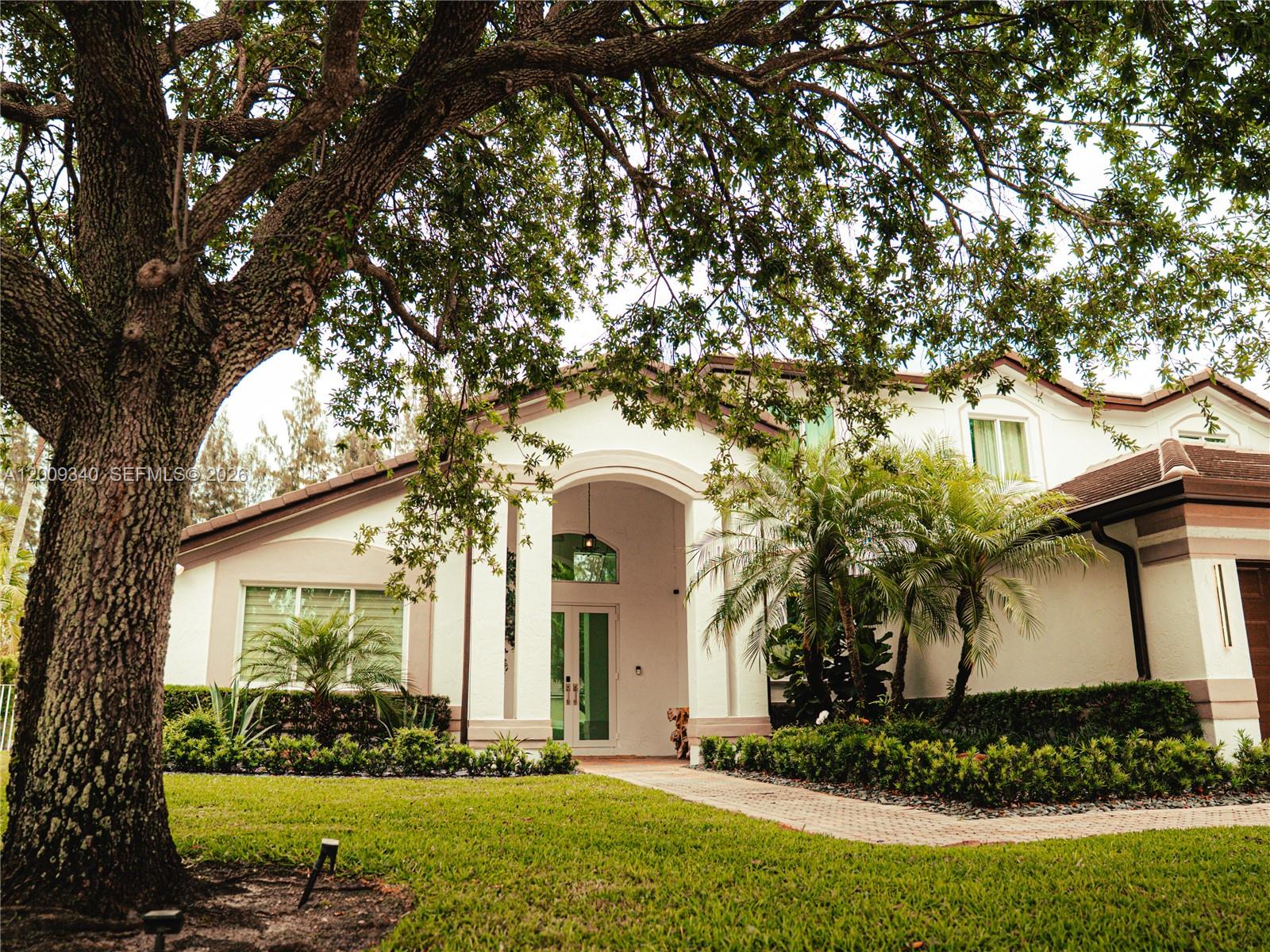A large oak tree stands in front of a white house with a covered entryway — 3761 SW 144th Ave, Miramar FL 33027, MIRAMAR, FL
