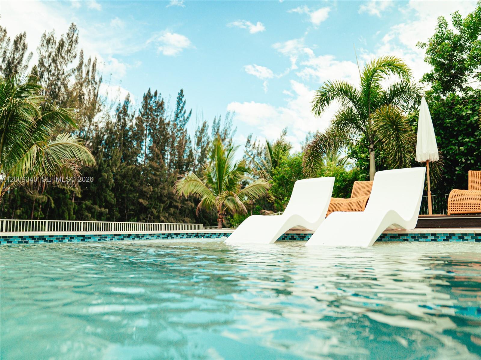 Two white lounge chairs sit in a swimming pool next to a white umbrella — 3761 SW 144th Ave, Miramar FL 33027, MIRAMAR, FL