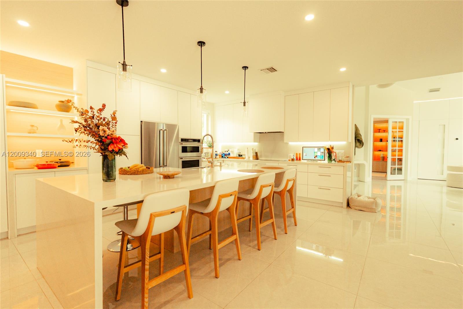 A modern white kitchen features a large island with bar seating and recessed lighting — 3761 SW 144th Ave, Miramar FL 33027, MIRAMAR, FL