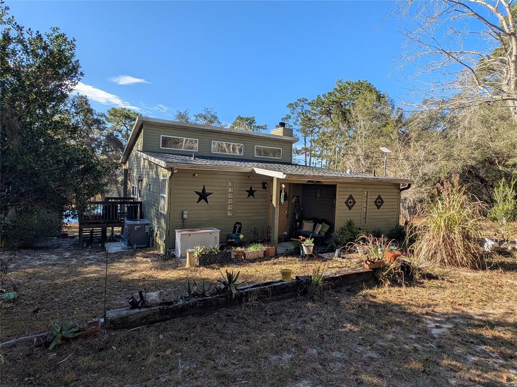 A green, single-story house with a covered porch and a wooden retaining wall in front — 14730 SE 61ST STREET ROAD, OCKLAWAHA, FL