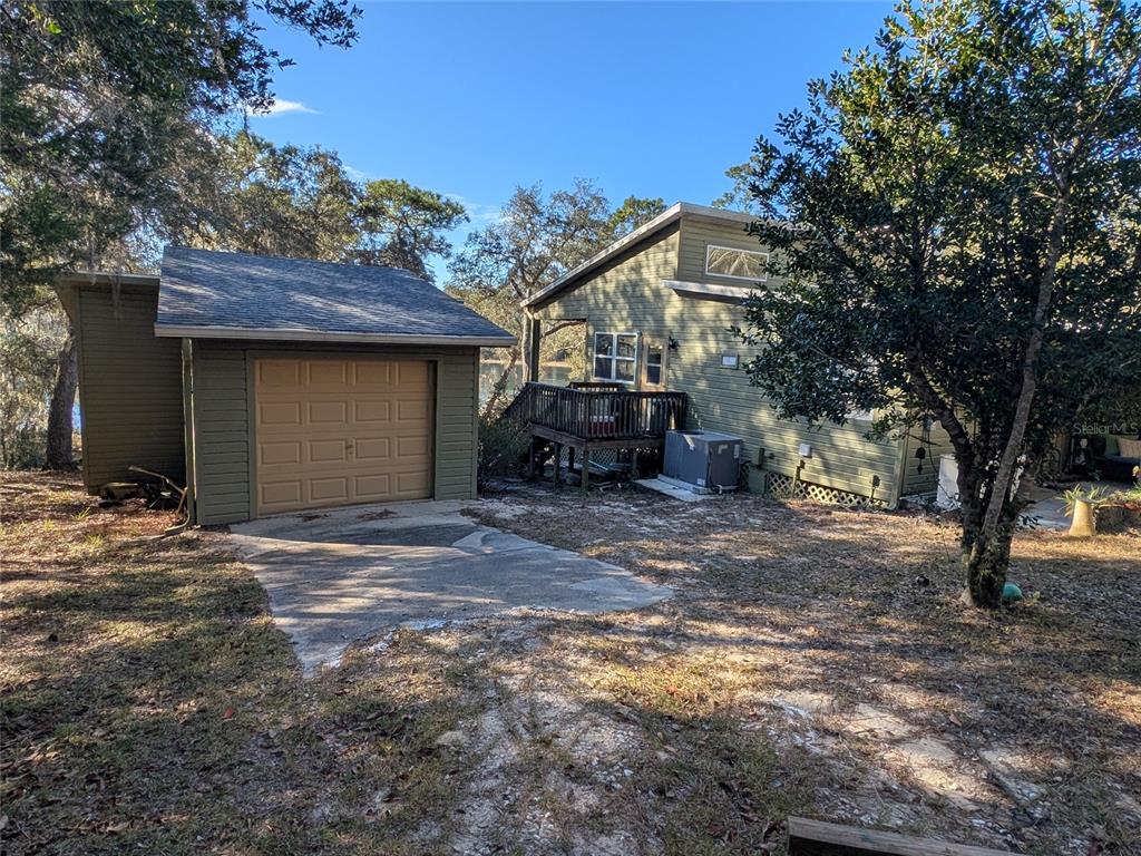 A green house with a detached garage and a wooden deck sits on a lot — 14730 SE 61ST STREET ROAD, OCKLAWAHA, FL