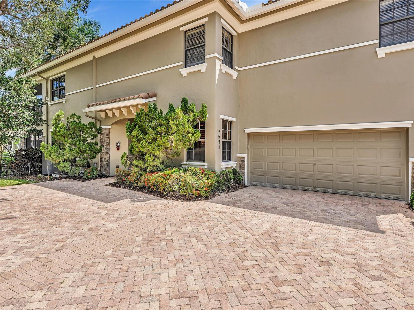 A two-story house exterior features a beige stucco facade, a brick paver driveway, and a garage — 7531 Old Thyme Court, Parkland FL 33076, PARKLAND, FL