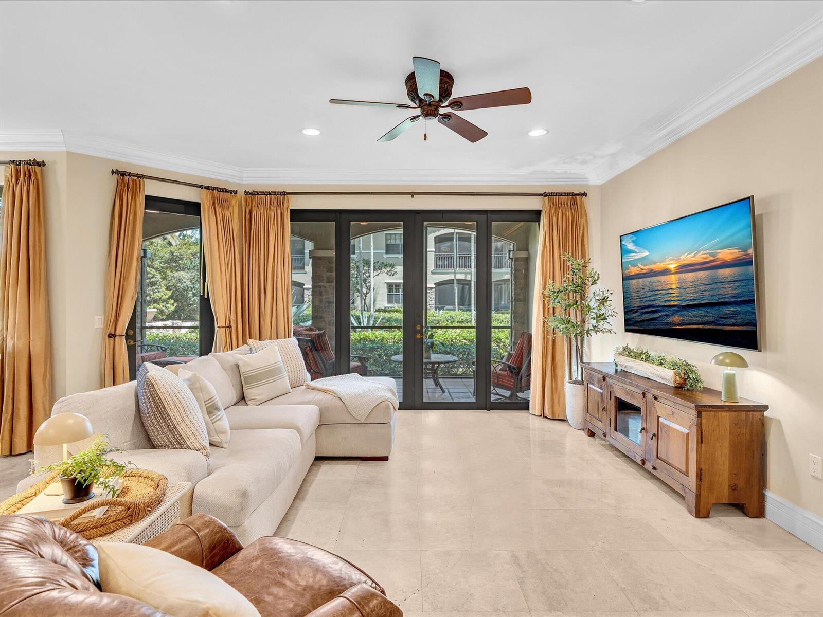 A living room features a sectional sofa, a wooden media console, and glass patio doors — 7531 Old Thyme Court, Parkland FL 33076, PARKLAND, FL