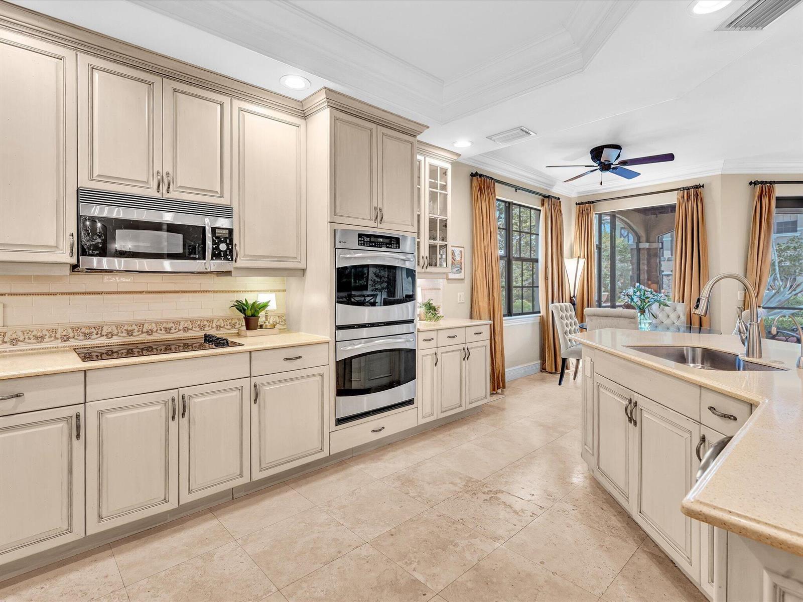 A kitchen with cream-colored cabinets, stainless steel appliances, and a central island with a sink — 7531 Old Thyme Court, Parkland FL 33076, PARKLAND, FL