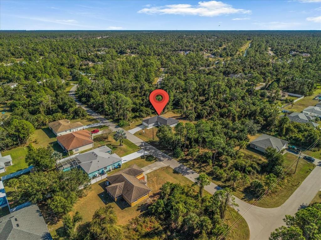 An aerial view shows a single-story house with a red pin on a wooded lot — 5565 LAVENDER AVENUE, NORTH PORT, FL