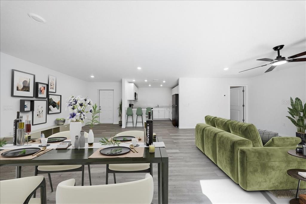 An open-concept living and dining area features white walls, gray wood-look flooring, and green furniture — 5565 LAVENDER AVENUE, NORTH PORT, FL