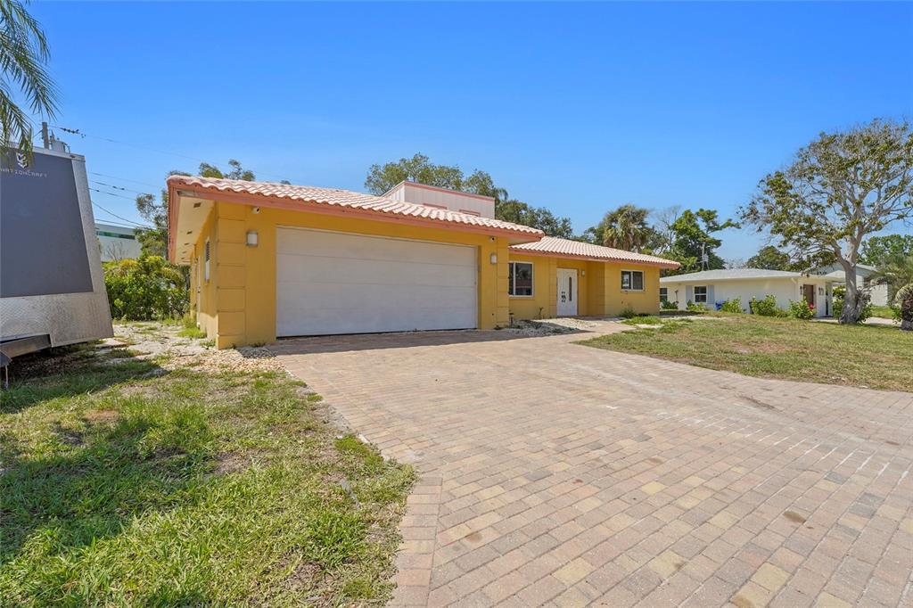 A yellow single-story house features a two-car garage and a paved driveway — 1613 IDLE LANE, SARASOTA, FL