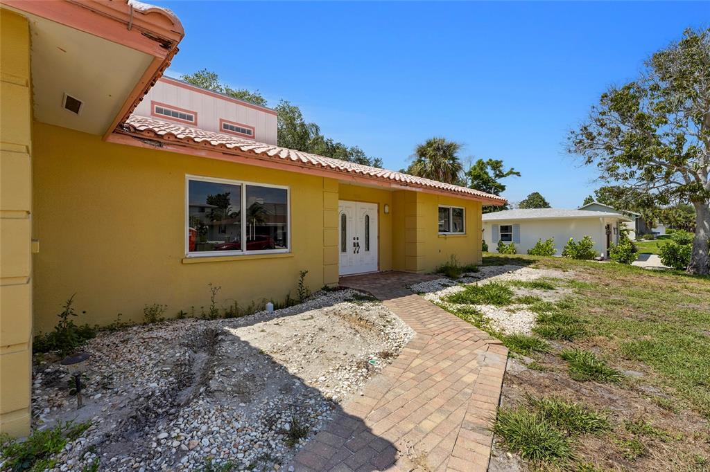 A yellow house with a brick walkway leading to a double front door — 1613 IDLE LANE, SARASOTA, FL
