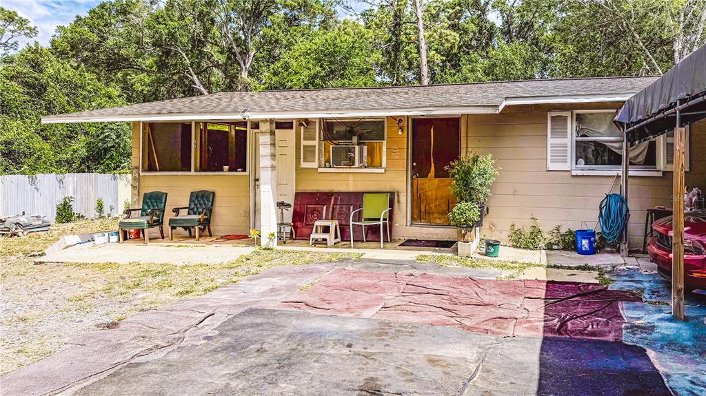 The exterior of a single-story house features a concrete patio, outdoor seating, and a carport — 6722 SW 53RD AVENUE, GAINESVILLE, FL