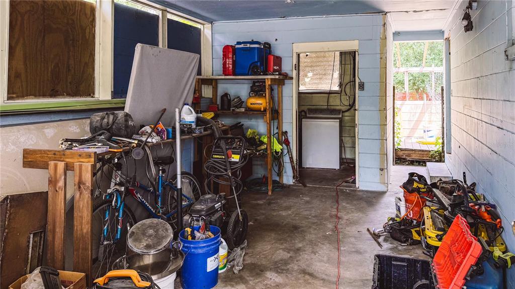 A cluttered, unfinished utility room or porch with a concrete floor and blue wood siding — 6722 SW 53RD AVENUE, GAINESVILLE, FL