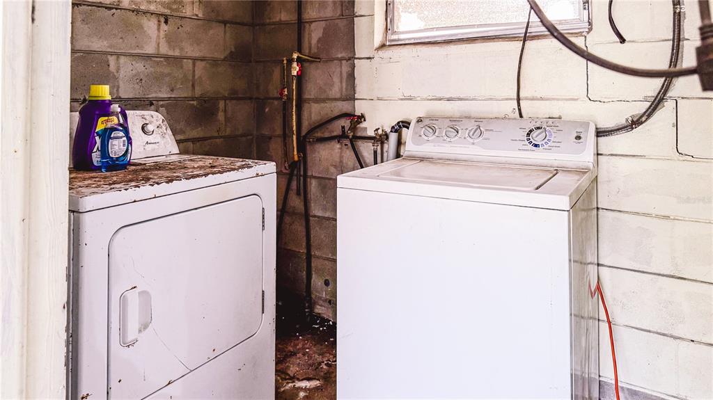 A laundry room features a white washing machine and dryer against unfinished concrete block walls — 6722 SW 53RD AVENUE, GAINESVILLE, FL