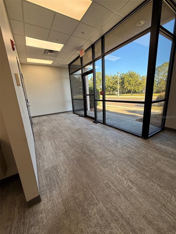 An empty office space with carpeted flooring, a drop ceiling, and large floor-to-ceiling windows — 13859 PROGRESS BOULEVARD UNIT 200, ALACHUA, FL