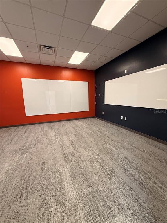 An office room features orange and dark walls, whiteboards, and gray patterned carpet flooring — 13859 PROGRESS BOULEVARD UNIT 200, ALACHUA, FL