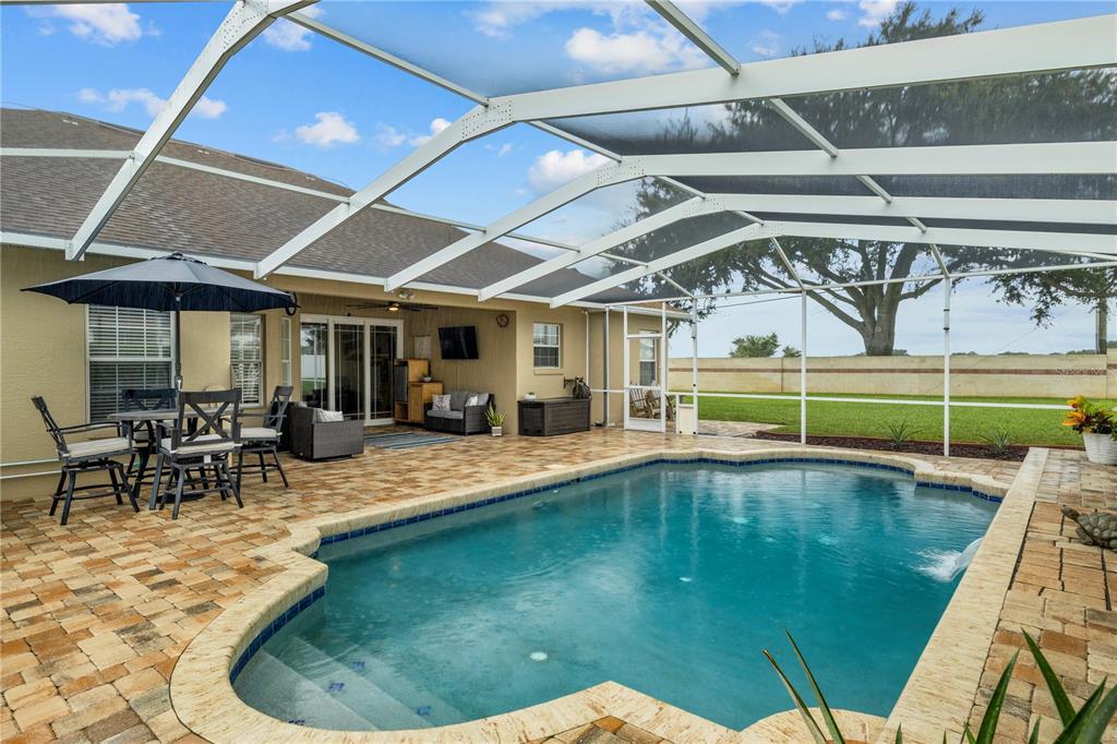 A screened-in patio features a swimming pool, outdoor dining furniture, and a paved deck — 651 HART LAKE DRIVE, WINTER HAVEN, FL