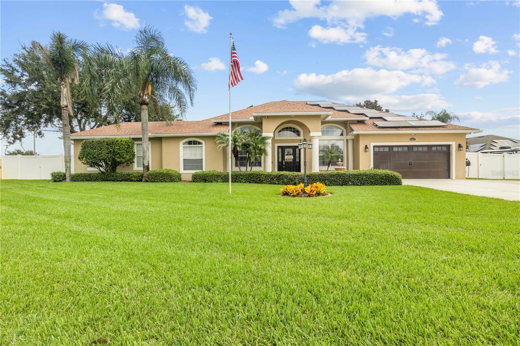 A single-story house with a tan stucco exterior, a brown roof, and a front lawn — 651 HART LAKE DRIVE, WINTER HAVEN, FL