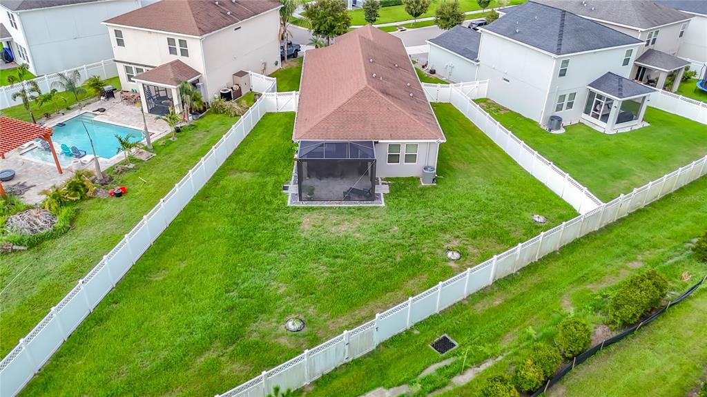 An aerial view of a residential backyard featuring a screened patio and white vinyl fencing — 7531 ASHCROFT DRIVE, WESLEY CHAPEL, FL