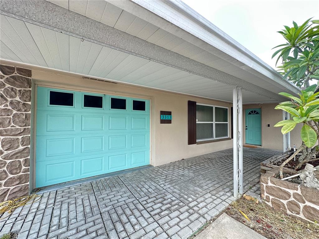 A house exterior features a turquoise garage door, a matching front door, and a paved driveway — 3313 BRIAR CLIFF DRIVE, HOLIDAY, FL