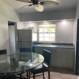 A kitchen with a glass dining table, stainless steel refrigerator, and gray cabinetry — 3100 EUNICE AVENUE, ORLANDO, FL
