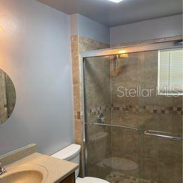 A bathroom features a beige vanity, a toilet, and a tiled shower with glass doors — 3100 EUNICE AVENUE, ORLANDO, FL