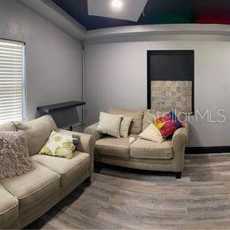 A living room features two beige sofas, light wood-look flooring, and a dark ceiling — 3100 EUNICE AVENUE, ORLANDO, FL