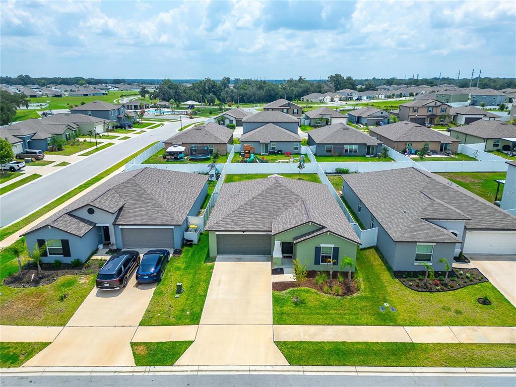 An aerial view shows three suburban houses with driveways and green lawns in a neighborhood — 4450 COZY CONDOR COURT, BARTOW, FL