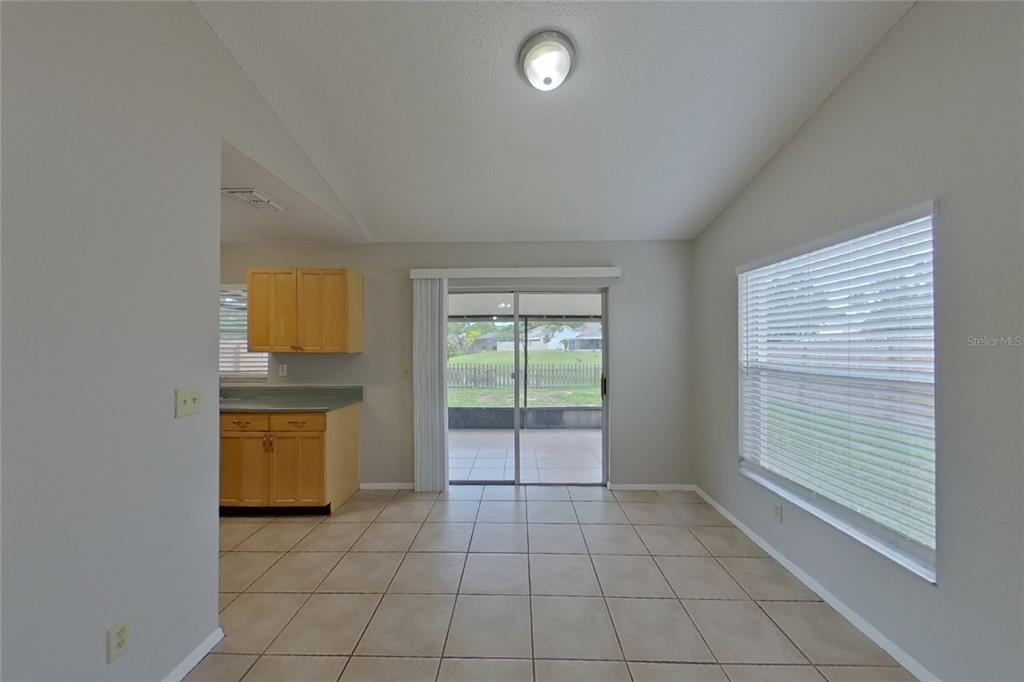 A dining area with tile floors, a sliding glass door, and an adjacent kitchen — 13311 LARAWAY DRIVE, RIVERVIEW, FL
