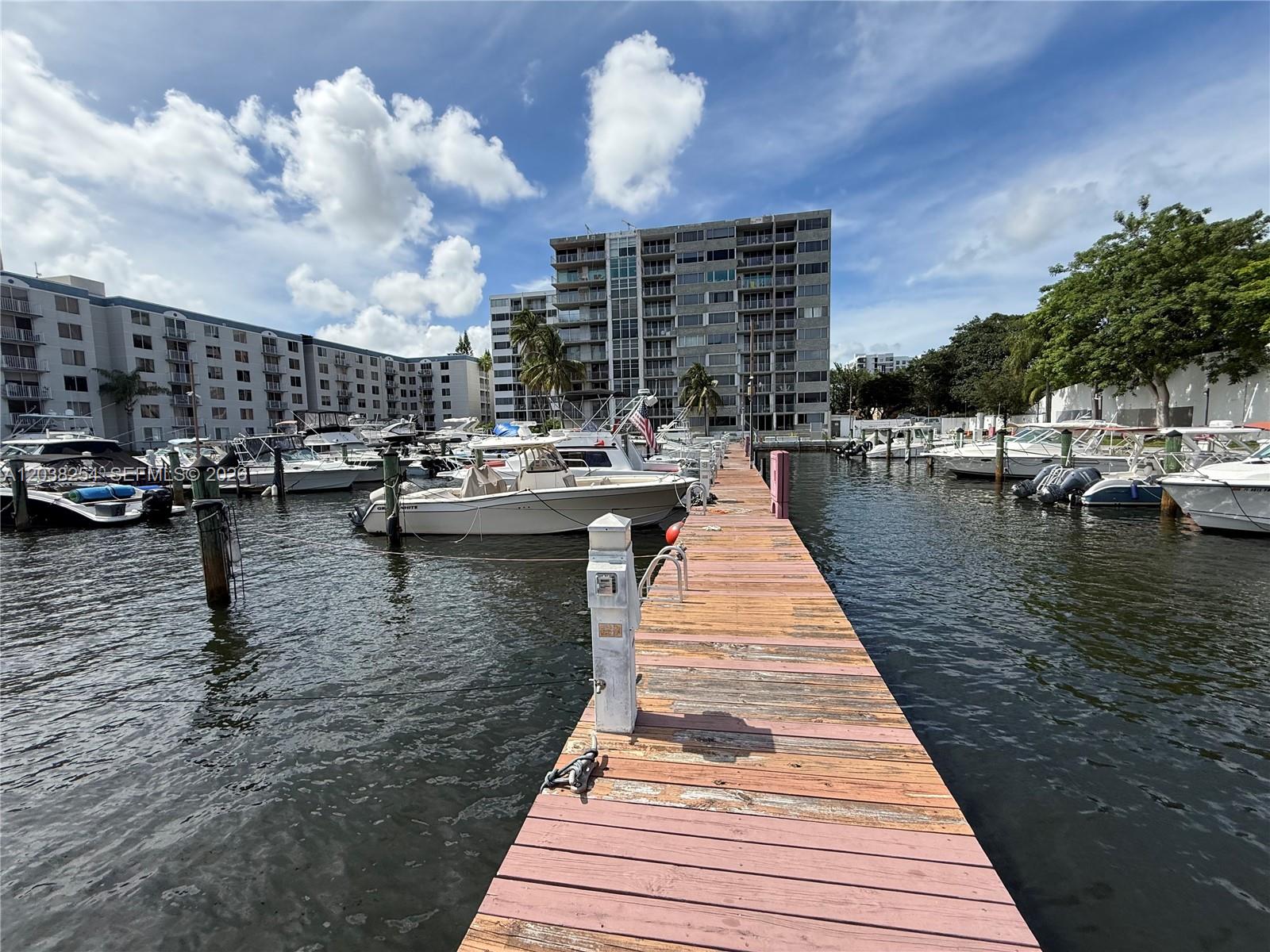A wooden dock extends into a marina filled with boats in front of apartment buildings — 1700 NW North River Dr, Miami FL 33125, MIAMI, FL