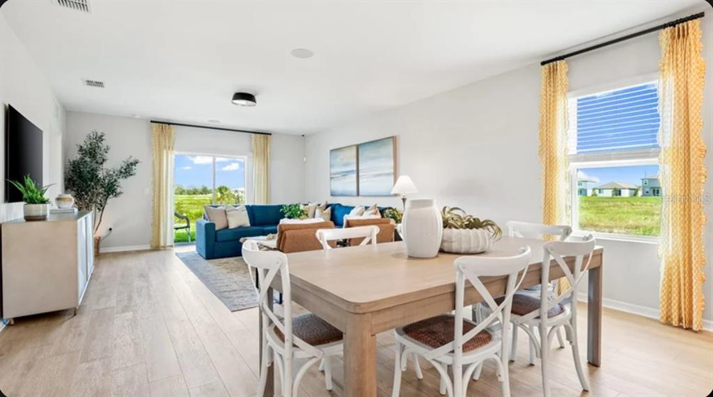 A bright open-concept living and dining area features light wood floors and yellow curtains — 6565 EQUINOX LANE, NORTH FORT MYERS, FL